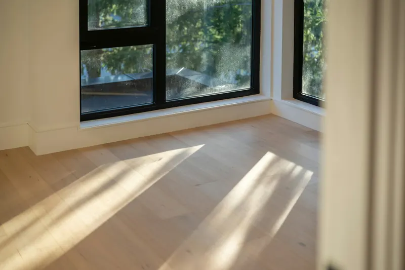 大きな窓から差し込む光が、明るい木の床に伸びている部屋